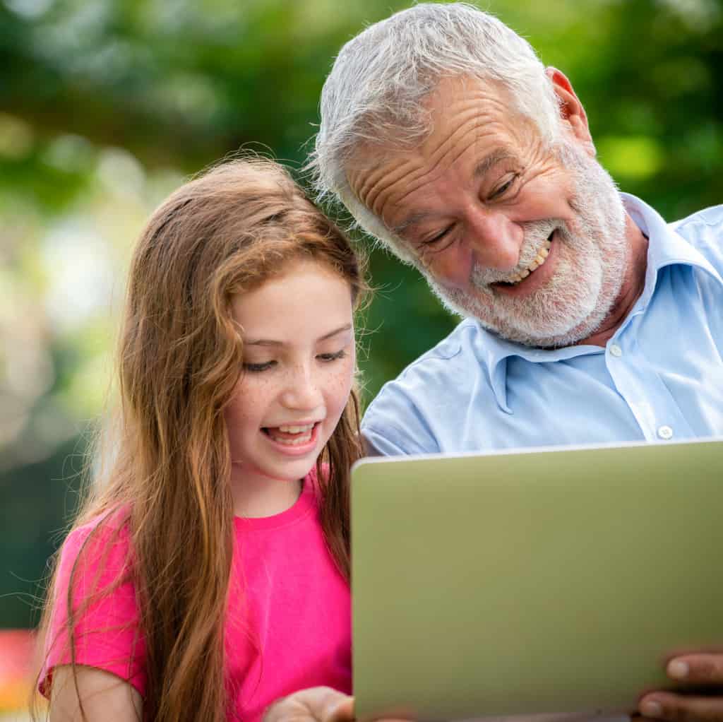 Großvater und Enkelin schauen sich einen Newsletter im Laptop an