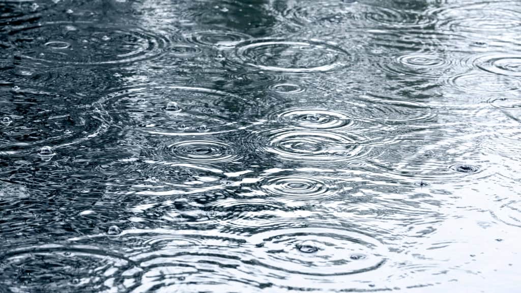 Regentropfen fallen auf die Wasseroberfläche