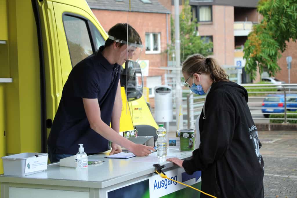 Ein Teammitglied vom VSR-Gewässerschutz berät eine Brunnenbesitzerin an einem Informationsstand in einer deutschen Stadt vor dem Labormobil