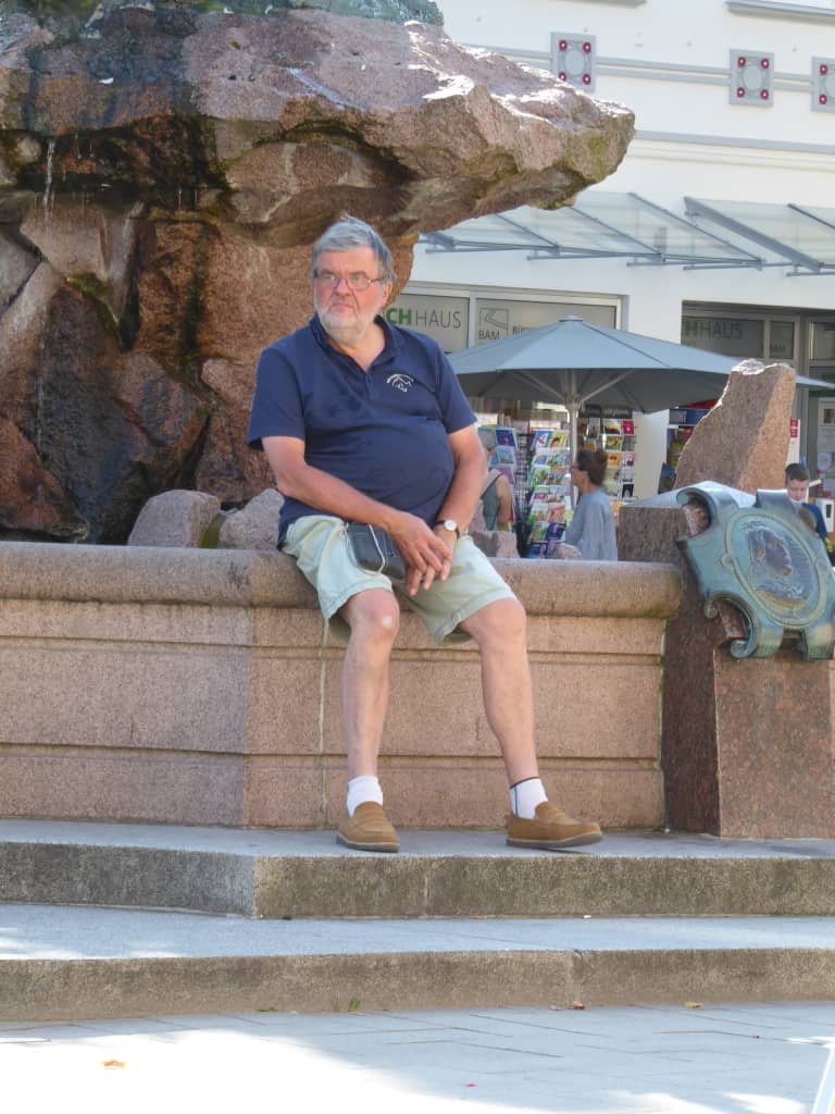 Michael Cohausz sitzt in der Sonne auf einem Brunnen