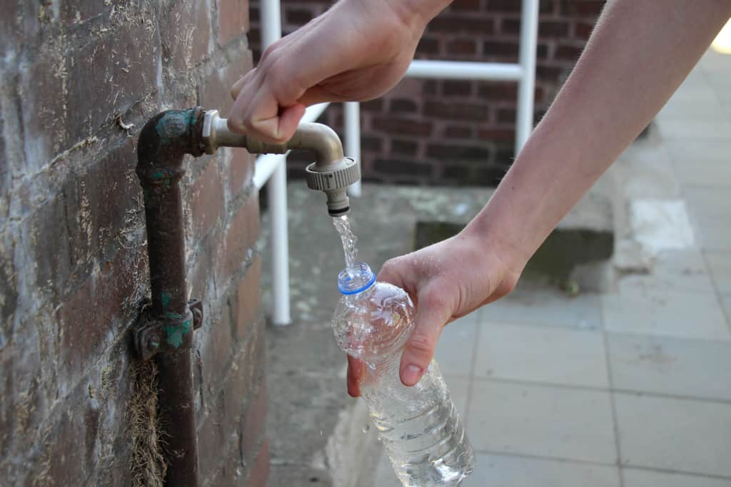 Eine Brunnenwasserprobe wird abgefüllt als Symbol für eine Brunnenwasseranalyse