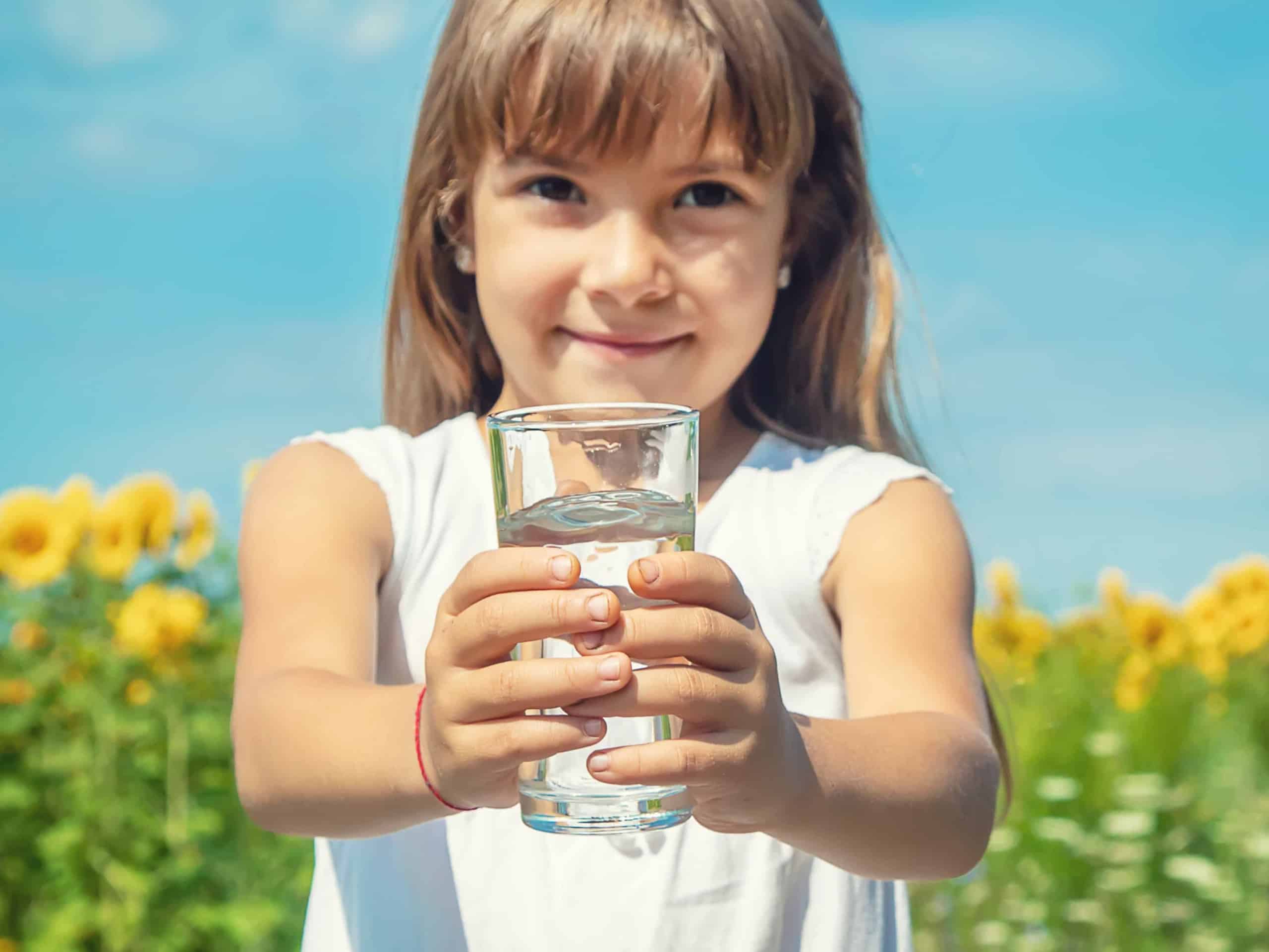 Ein Mädchen trinkt aus einem Glas. Als Symbol für eine Trinkwasseranalyse.