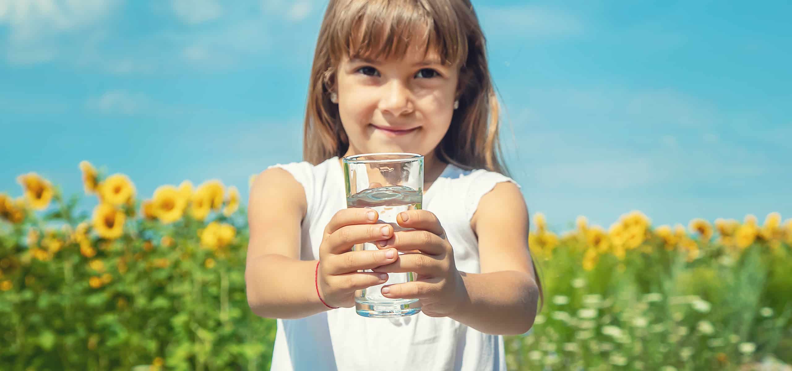 Mädchen hällt ein Glas mit Wasser in Händen