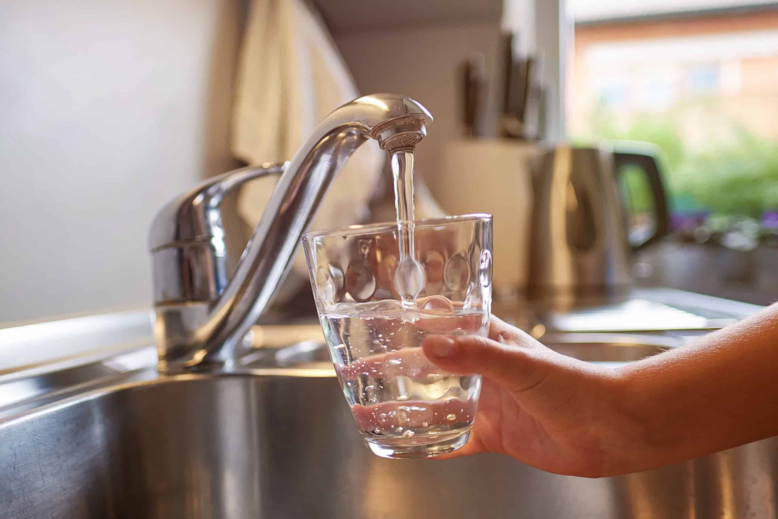 Wasser aus dem Wasserhahn wird in der Küche in ein Glas gefüllt