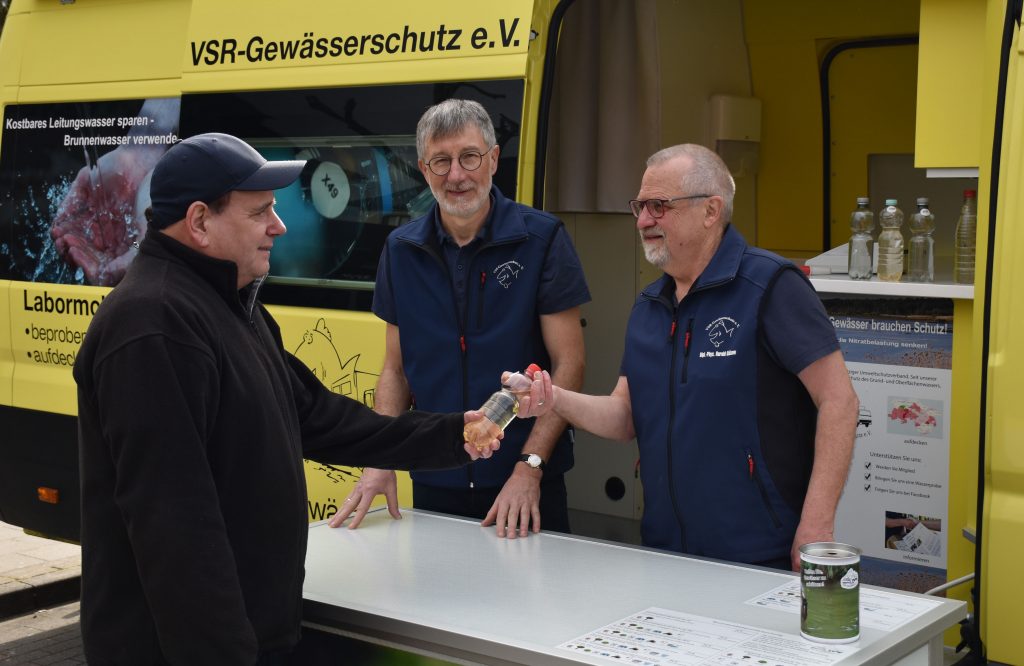 Ehrenamtler Heinz-Theo van Wickeren (mitte) und Harald Gülzow (rechts) nehmen von einen Brunnenbesitzer seine Wasserprobe entgegen.