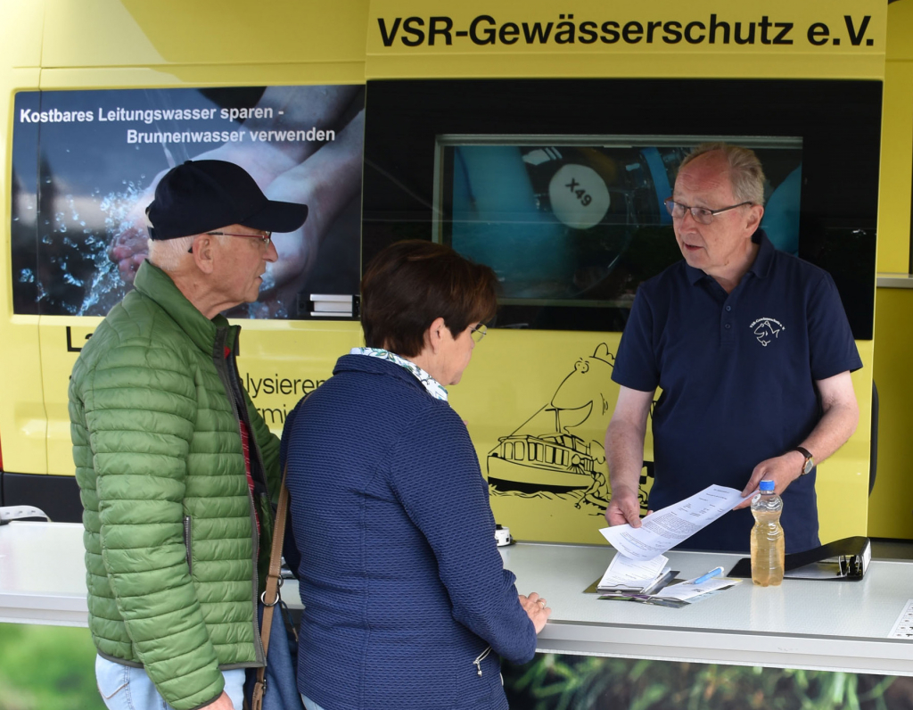 Heinz-Wilhelm Hülsmans (dritte Person von links), ehrenamtlicher Mitarbeiter beim  VSR-Gewässerschutz, berät Brunnenbesitzer am Informationsstand des Labormobils.