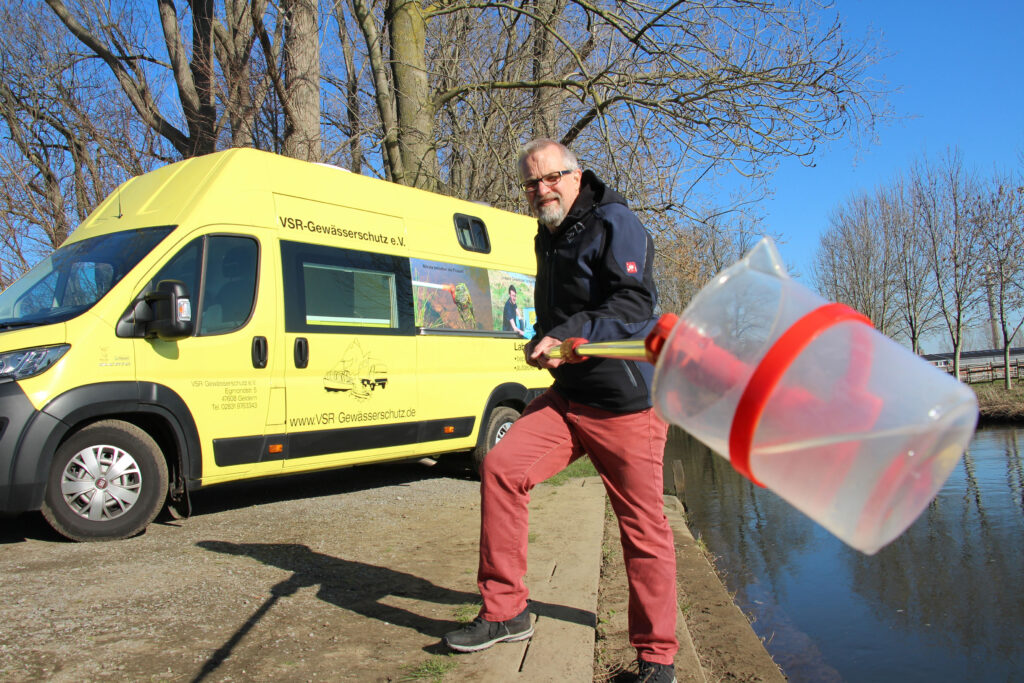 Harald Gülzow nimmt an einem Fluss eine Probe