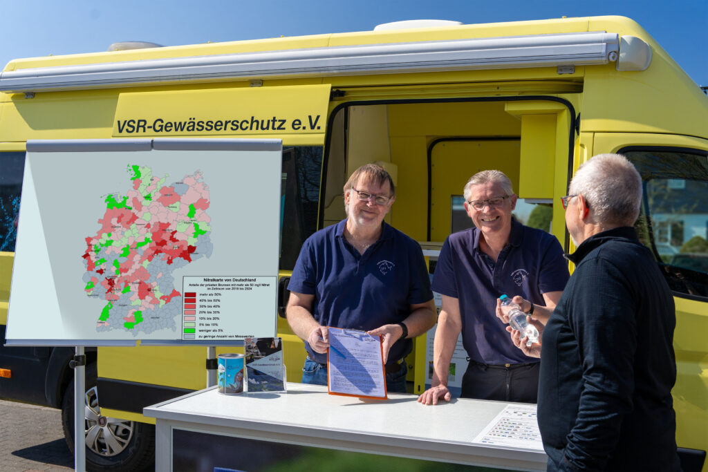 Arno Mittelmeyer und Matthias Ahlbrecht beraten einen Brunnenbesitzer mit Nitratkarte Deutschland vor einem Labormobil des VSR-Gewässerschutz e.V. Fotograf Ruben Wiltsch
