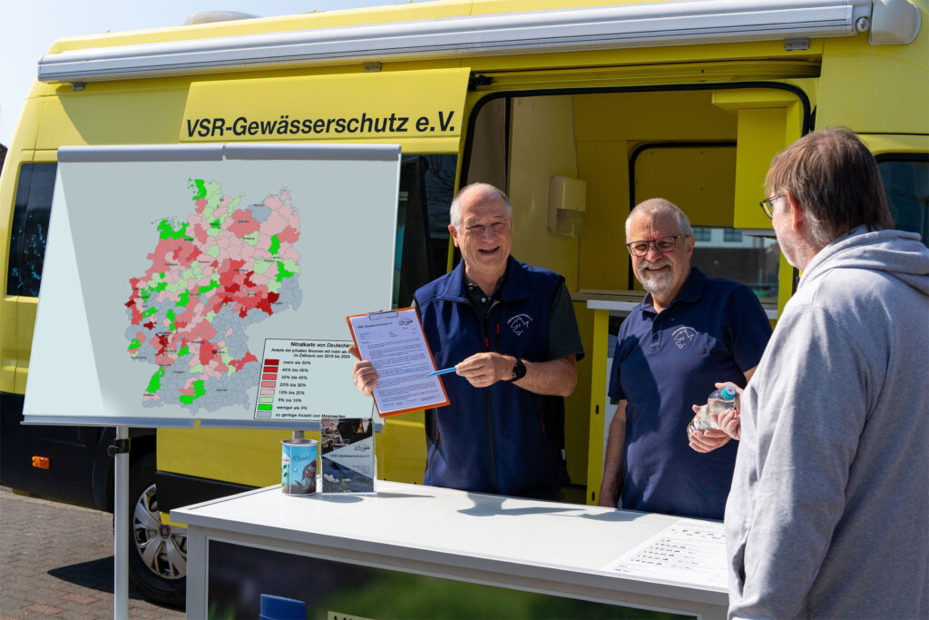 Georg Stüker und Harald Gülzow Beraten einen Brunnenbesitzer mit Nitratkarte Deutschland vor einem Labormobil des VSR-Gewässerschutz e.V. Fotograf Ruben Wiltsch
