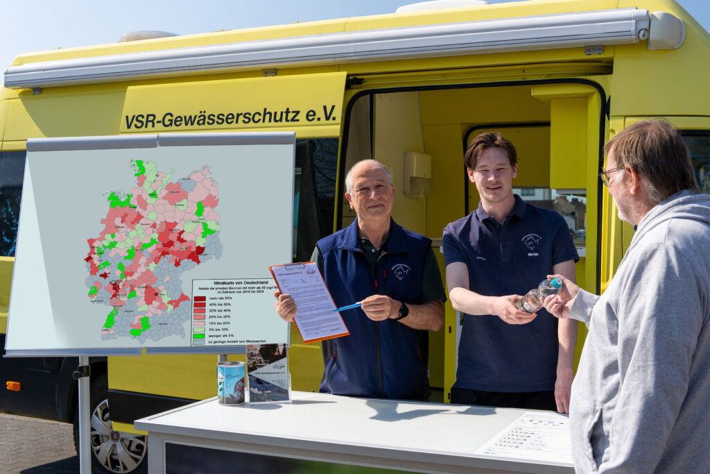 Georg Stüker und Milan Toups beraten einen Brunnenbesitzer mit Nitratkarte Deutschland vor einem Labormobil des VSR-Gewässerschutz e.V. Fotograf Ruben Wiltsch