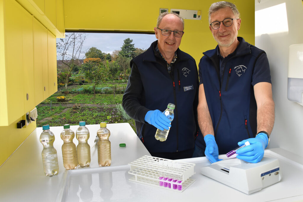 Heinz-Wilhelm Hülsmans (links) und Heinz-Theo van Wickeren (rechts) untersuchen eine Brunnenwasserprobe im Labormobil vom VSR-Gewässerschutz