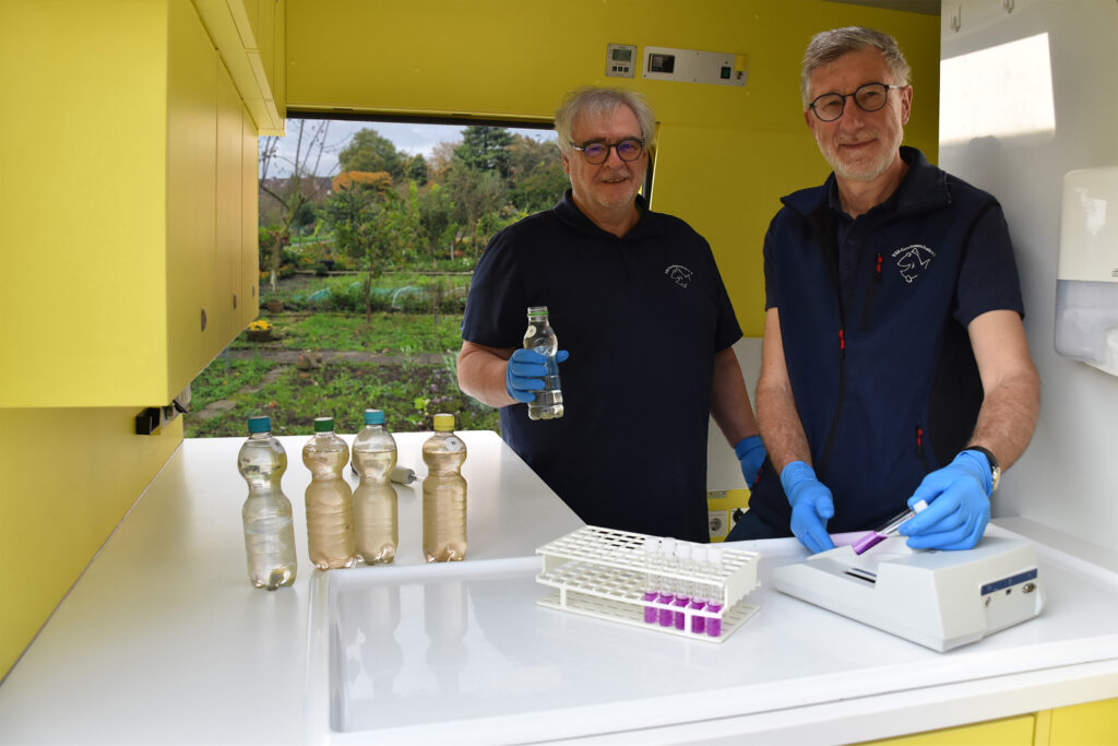 Helmut Hartmann (links) und Heinz-Theo van Wickeren (rechts) untersuchen eine Brunnenwasserprobe im Labormobil vom VSR-Gewässerschutz