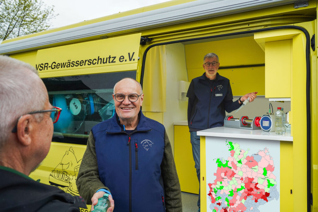 Dieter Knetsch (mitte) und Heinz-Theo van Wickeren (rechts) beraten einen Brunnenbesitzer und untersuchen eine Brunnenwasserprobe, Fotograf Ruben Wiltsch