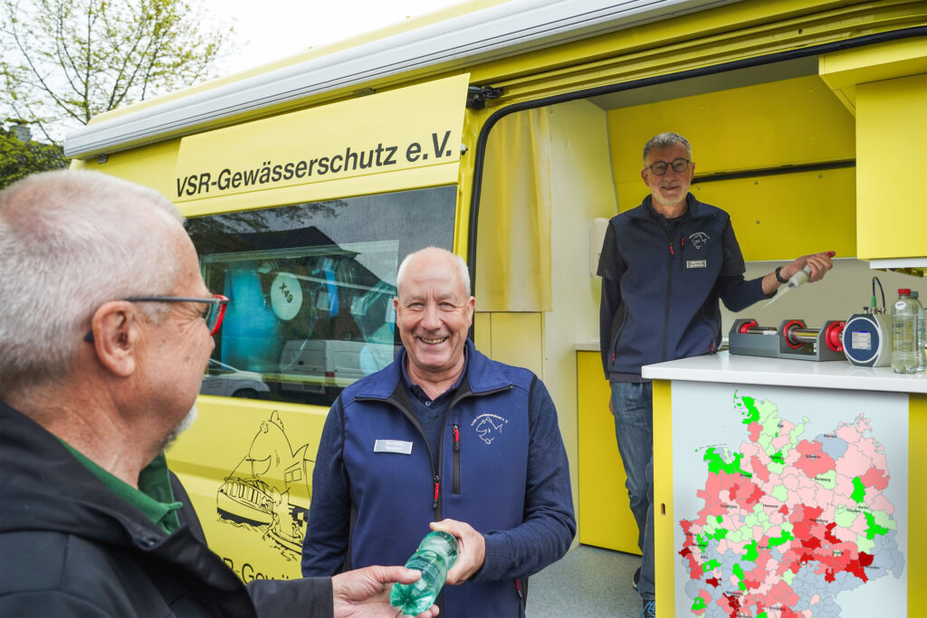 Gunther Hagner (mitte) und Heinz-Theo van Wickeren (rechts) beraten einen Brunnenbesitzer und untersuchen eine Brunnenwasserprobe, Fotograf Ruben Wiltsch