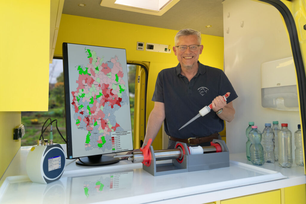 Matthias Ahlbrecht untersucht eine Brunnenwasserprobe, mit Nitratkarte von Deutschland im Labormobil vom VSR-Gewässerschutz